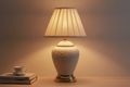 Ceramic bedside lamp with classic base and soft fabric shade on a plain neutral background, realistic photo