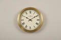 Classic round wall clock on a plain neutral background, realistic photo