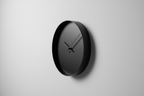Contemporary black wall clock side view with minimalist design on a plain neutral background, realistic photo