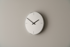Modern minimalist wall clock on a plain neutral background, realistic photo.