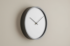 Modern minimalist wall clock side view on a plain neutral background, realistic photo